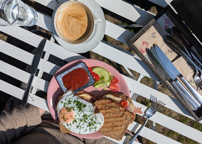 Frühstücksbrot mit Ei und Gemüse neben einer Tasse Kaffee