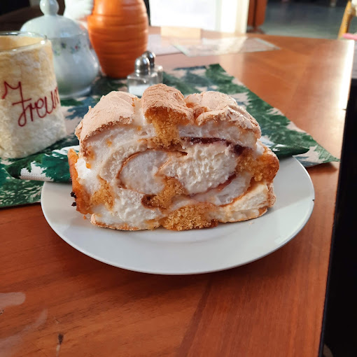 Ein Stück mit Creme gefüllte Mehlspeise auf einem weißen Teller