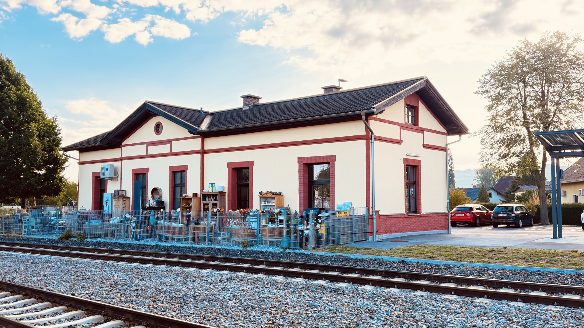 Das Vintage Café im ehemaligen Bahnhof Bad Erlach mit Dekoration vor dem Gebäude und Gleisen im Vordergrund